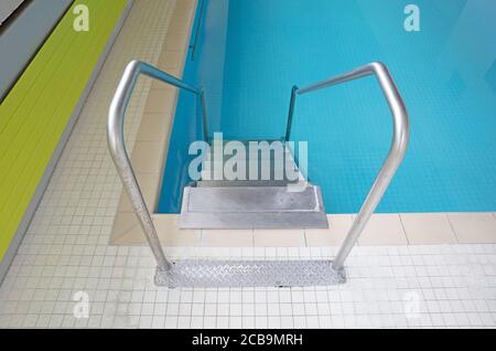 Scale metalliche in una piscina interna Foto Stock
