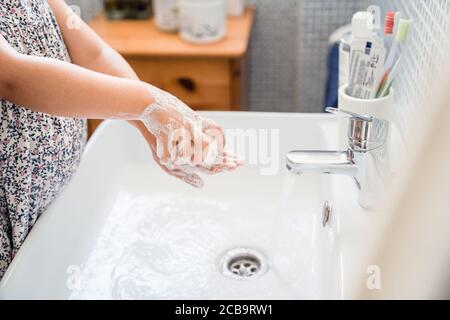 La bambina lava le mani con una saponetta in lavandino sotto acqua corrente di rubinetto Foto Stock