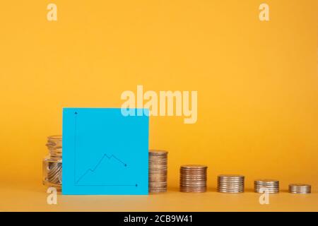 crisi finanziaria. pila di monete con un grafico per una caduta. Foto Stock