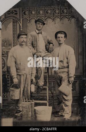 Tre pittori, disposti su e intorno a una scala, con spazzole, secchio, e lattina di vernice, 1870-80s.