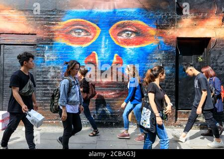 La gente passa davanti a un dipinto di lavoro pubblico Dale Grimshaw in Hanbury Street, fuori Brick Lane, East End, Londra Foto Stock