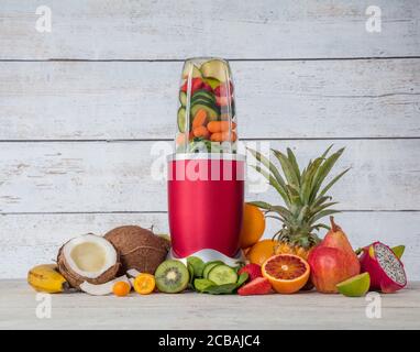 Frullatore mixer con pezzi di frutta ingredienti, posto in interni in legno. Bibita salutare e stile di vita Foto Stock