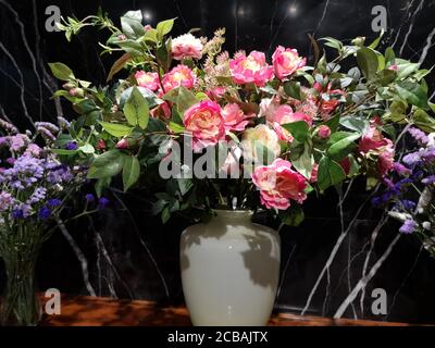 bel bouquet di rose rosa e gialle in vaso bianco su tavola di legno sfondo marmo nero, fiori artificiali Foto Stock