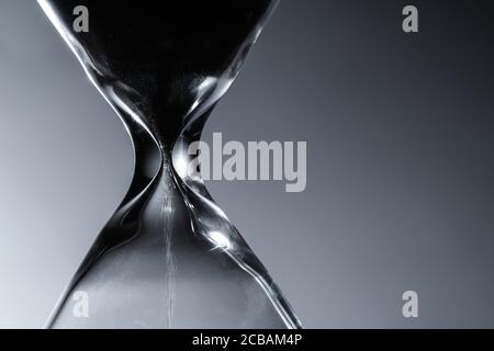 Ampia clessidra o vetroresina in un primo piano scuro. Tecnologia dell'orologio dei tempi vecchi. Foto Stock