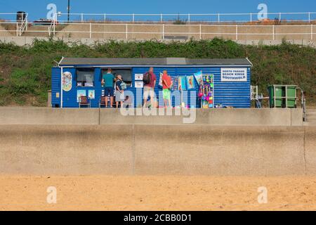 Il mare di Suffolk, vista in estate delle persone che si accodano al chiosco della spiaggia di North Parade lungo il lungomare di Southwold sulla costa di Suffolk, Inghilterra, Regno Unito Foto Stock