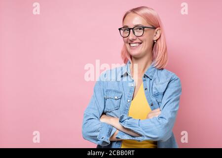 Giovane gioiosa donna con capelli rosa tinti e occhiali sorridenti alla macchina fotografica. Foto Stock