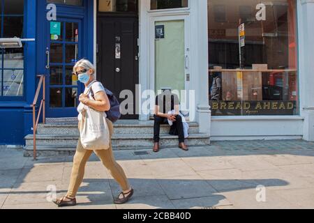 Un uomo si siede stanco fuori da un negozio che è chiuso in Hampstead High Street come affari vicino tutto il Regno Unito a causa del Coronavirus o Covid-19. Foto Stock