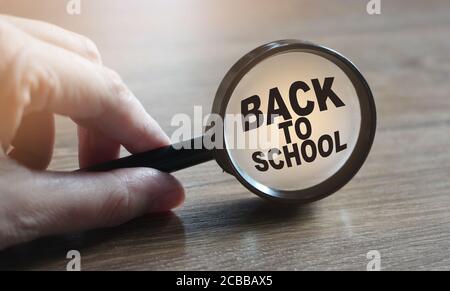 Torna a scuola parole sotto lente d'ingrandimento in mano. Concetto di istruzione Foto Stock