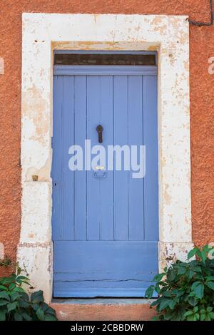 Una porta dipinta di blu nel colorato villaggio francese di Roussillon Foto Stock