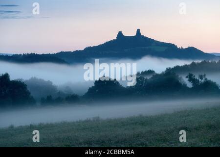 Rovine del vecchio castello di Trosky nel paradiso Boemo, Repubblica Ceca. Le rovine consistono di due torri devasted sulla collina boscosa. Mattina paesaggio con nebbie Foto Stock