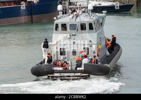 I migranti portati a terra dalle forze di frontiera del porto di dover.un numero crescente di migranti ha navigato in piccole imbarcazioni dalle acque territoriali francesi nella Manica, dove sono legalmente portati a terra dalle forze di frontiera britanniche. I migranti sono quindi in grado di chiedere asilo nel Regno Unito. Foto Stock