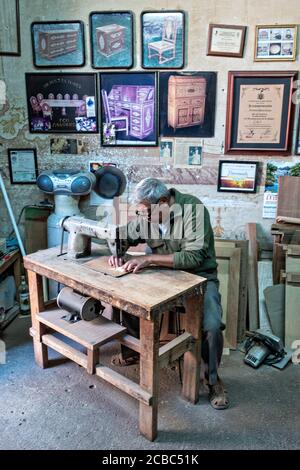 L'artista messicano Francisco Aguirre crea disegni in legno intarsiato utilizzando una macchina da cucire dotata di una lama fine presso il suo laboratorio di studio a Jalostoltitlan, Jalisco state, Messico. Aguirre è stato nominato un grande maestro dell'arte popolare messicana e i suoi oggetti fatti a mano sono raccolti in tutto il mondo. Foto Stock