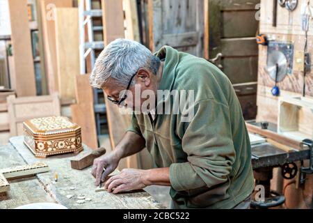 L'artista messicano Francisco Aguirre crea disegni in legno intarsiato utilizzando una macchina da cucire dotata di una lama fine presso il suo laboratorio di studio a Jalostoltitlan, Jalisco state, Messico. Aguirre è stato nominato un grande maestro dell'arte popolare messicana e i suoi oggetti fatti a mano sono raccolti in tutto il mondo. Foto Stock