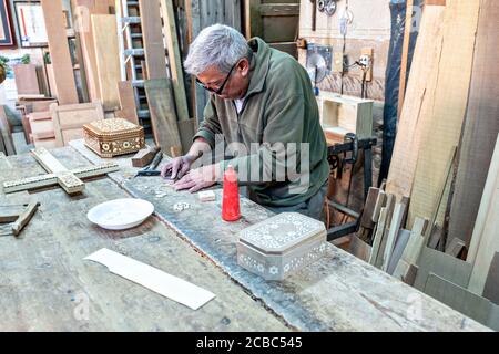 L'artista messicano Francisco Aguirre crea disegni in legno intarsiato utilizzando una macchina da cucire dotata di una lama fine presso il suo laboratorio di studio a Jalostoltitlan, Jalisco state, Messico. Aguirre è stato nominato un grande maestro dell'arte popolare messicana e i suoi oggetti fatti a mano sono raccolti in tutto il mondo. Foto Stock