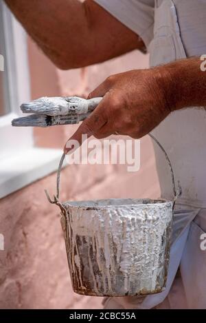 Hampshire, Inghilterra, Regno Unito. 2020. Pittore decoratore pittura piccole finestre su una casa rurale. Painters bollitore e spazzole. Foto Stock