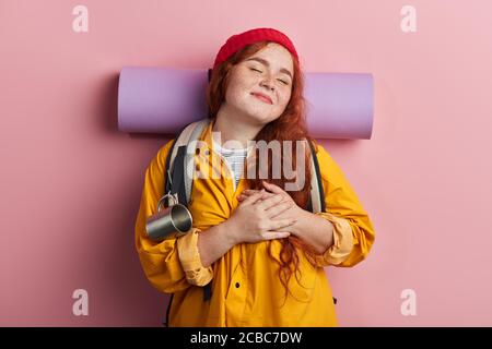 L'escursionista allegro con gli occhi chiusi mantiene le palme sul sentire. Espra la sua tenera sensazione, emozione. Isolato sfondo rosa, scatto studio, amo, mi manchi. ho Foto Stock