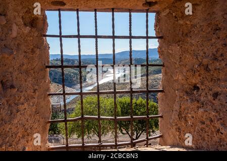 Vista attraverso una finestra del castello con griglia in ferro battuto (Griglia del castello) Foto Stock