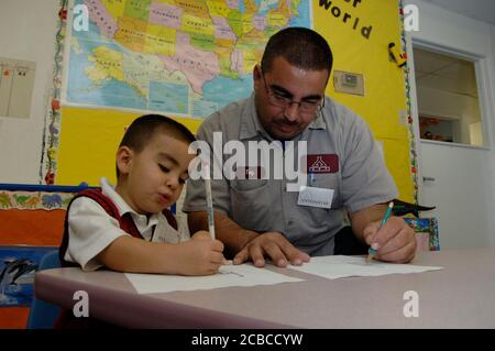 San Antonio Texas USA: Il padre della classe operaia e il figlio dell'asilo partecipano a un programma presso la scuola prescolare di AT Head Start che offre una cena gratuita e tempo per la famiglia per i bambini piccoli e i loro genitori. Dopo cena, gli adulti si incontrano per una sessione di consulenza di gruppo sulle tecniche genitoriali, per poi riunirsi ai loro figli per leggere e scrivere insieme. © Bob Daemmrich Foto Stock