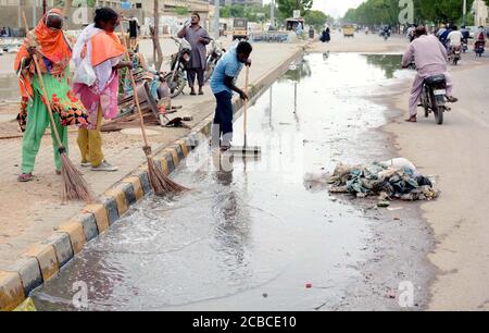 Sudori del governo locale distretto occupato nella pulizia dell'acqua piovana in una strada dopo il deadpour della stagione monsone situato nella zona di Korangi a Karachi Mercoledì, 12 agosto 2020. Foto Stock