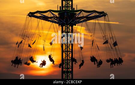 Monaco, Germania. 12 agosto 2020. Numerose persone cavalcano una giostra a catena nel Parco Olimpico durante il tramonto. Credit: Sven Hoppe/dpa/Alamy Live News Foto Stock