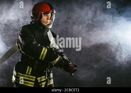 vigili del fuoco eroe moderno caucasico in uniforme non temere di pericolo, alla ricerca di persone da salvare, utilizzando corde, martelli e altre attrezzature hanno bisogno di proteggere Foto Stock