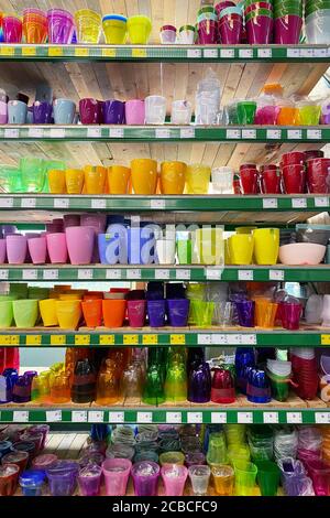 Varietà di vasi di fiori sono venduti al negozio. File di diverse pentole colorate per piante da interno su scaffali in un supermercato. Vista verticale. Foto Stock