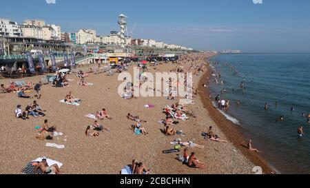 Brighton, UK - 10 agosto 2020: Un sacco di persone sulla spiaggia e in mare godendo il tempo caldo. Foto Stock