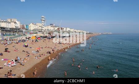 Brighton, UK - 10 agosto 2020: Un sacco di persone sulla spiaggia e in mare godendo il tempo caldo. Foto Stock