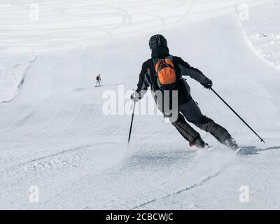Sciatore in discesa nera su una pista da sci. Vista dal retro. Foto Stock