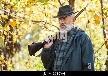 Caccia alla foresta sugli animali. Uomo anziano che tiene il fucile, sconvolto dopo la caccia in foresta Foto Stock