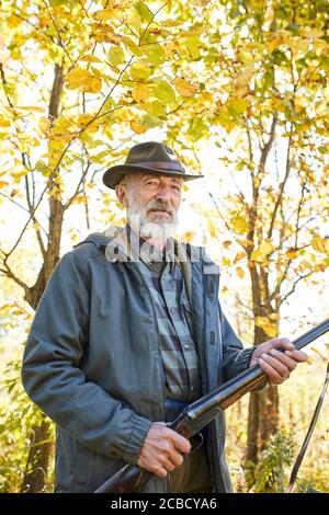 Ritratto di cacciatore anziano dopo la caccia di successo, un cacciatore esperto. Caccia in autunno. Cacciatore con fucile Foto Stock