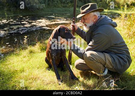 Pausa tempo dopo la caccia. Buon lavoro, caccia riuscita sul lago. L'uomo bearded caccia sulle anatre Foto Stock