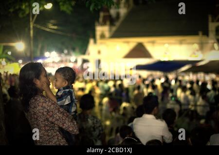 Larantuka, Indonesia. 2 aprile 2015. Una madre che conforta il suo bambino durante il servizio di massa della chiesa cattolica il giovedì di Maundy alla Cattedrale di Larantuka, l'isola di Flores, Indonesia. Foto Stock