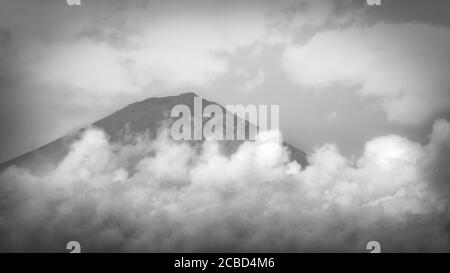 La cima del Monte Fuji si inculica attraverso le nuvole come visto da Fujinomiya, Giappone. Foto Stock