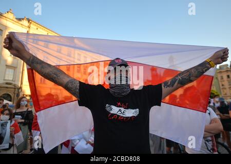 Cracovia, Polonia. 12 agosto 2020. Durante la manifestazione un manifestante detiene la bandiera bielorussa dell'indipendenza.centinaia di persone bielorusse che vivono a Cracovia e sostenitori locali si sono riuniti per un raduno di solidarietà con le proteste bielorusse in corso, nella piazza del mercato di Cracovia, fuori dal monumento Adam Mickiewicz. Credit: SOPA Images Limited/Alamy Live News Foto Stock