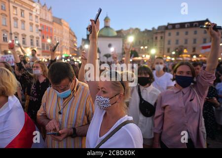 Cracovia, Polonia. 12 agosto 2020. I manifestanti hanno tenuto i telefoni con la luce accesa durante la dimostrazione.centinaia di persone bielorusse che vivono a Cracovia e i sostenitori locali si sono riuniti per un raduno di solidarietà con le proteste bielorusse in corso, nella piazza del mercato di Cracovia, fuori dal monumento Adam Mickiewicz. Credit: SOPA Images Limited/Alamy Live News Foto Stock