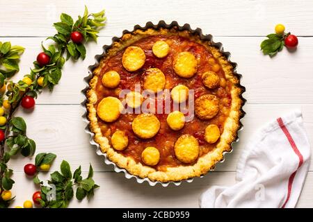 Torta aperta di pasta frolla con prugna di ciliegia, clafoutis di prugna mirobalana su sfondo bianco Foto Stock