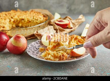 La mano della donna con una forchetta, rompe un pezzo di torta con pesche e pere, torte fatte in casa. Foto Stock