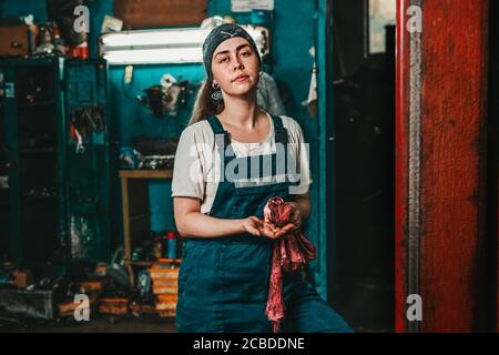 Uguaglianza di genere. Ritratto di una giovane donna forte in uniforme che lavora in un laboratorio, che si asciuga le mani con uno straccio. Verticale. Primo piano. Foto Stock