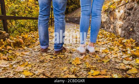 Accoppia i piedi dell'uomo e della donna in abiti alla moda che si levano in piedi all'aperto stile di vita con la natura autunnale sullo sfondo Foto Stock