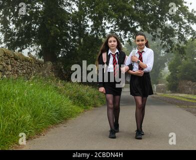 Camptoun, East Lothian, Scozia, Regno Unito, 13 agosto 2020. Ritorno a scuola: I gemelli Louisa e Imogen, che due giorni fa avevano compiuto 12 anni, partiscono dalla loro casa in una mattinata torbida per il loro primo giorno di scuola secondaria a North Berwick High come studenti S1. Hanno perso fuori durante i giorni normali di induzione in P7 dovuto il blocco pandemico di Covid-19 Foto Stock