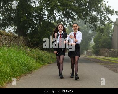 Camptoun, East Lothian, Scozia, Regno Unito, 13 agosto 2020. Ritorno a scuola: I gemelli Louisa e Imogen, che due giorni fa avevano compiuto 12 anni, partiscono dalla loro casa in una mattinata torbida per il loro primo giorno di scuola secondaria a North Berwick High come studenti S1. Hanno perso fuori durante i giorni normali di induzione in P7 dovuto il blocco pandemico di Covid-19 Foto Stock