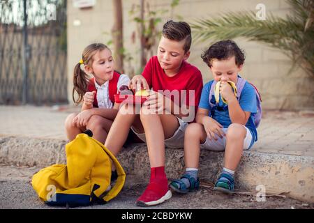 Gli allievi hanno uno spuntino all'aperto. Bambini, educazione e concetto nutrizionale Foto Stock