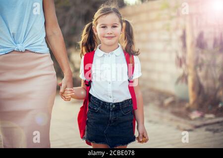 Ritorno a scuola. Concetto di cura dei genitori. Allievo e madre vanno a scuola. Foto Stock