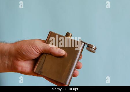 Fiasca in metallo per fianchi. Mano maschio sinistra con un matraccio piccolo aperto. Razza europea maschile, 43-45 anni. Stile di vita Foto Stock