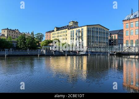 Vista verso lo storico paesaggio industriale a trascina su a. Giornata di sole nel mese di agosto 2020 dal parco cittadino Abackarna lungo Fiume Motala a Norrkoping Svezia Foto Stock