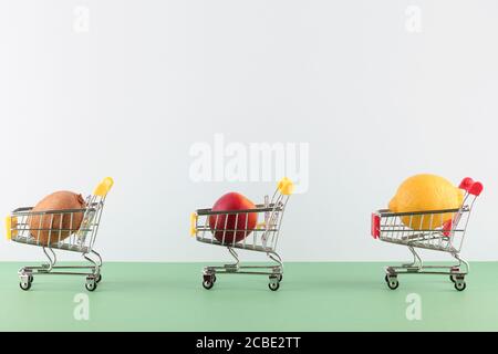 Cesto con frutta situato a distanza l'uno dall'altro su sfondo bianco e verde. Distanza sociale in luoghi pubblici Foto Stock