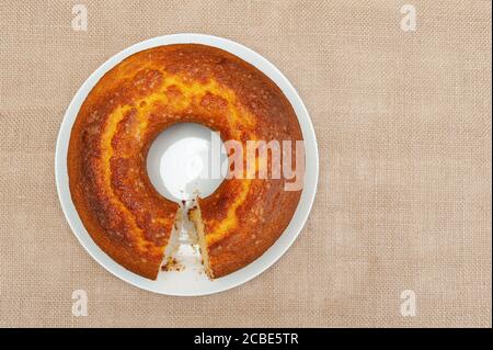 Torta di farina di mais (Bolo de Fuba) tagliata in stile brasiliano su un piatto bianco. Isolato su iuta. Vista dall'alto. Spazio di copia. Shot orizzontale. Foto Stock