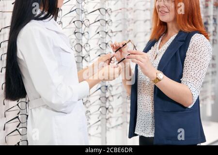 piacevole medico che dà i vetri del cliente per provarli. primo piano vista laterale ritagliato foto, occupazione, servizio Foto Stock