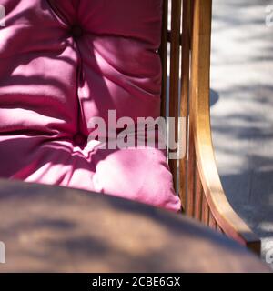 sedia in vimini con cuscini rosa su una veranda estiva in un caffè Foto Stock